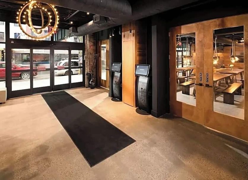 Hotel 1080 Brooklyn lobby entrance with glass doors, check-in kiosks and modern restaurant seating