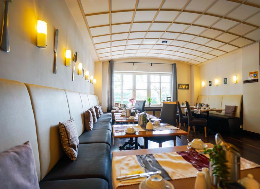 Hotel Am Schloss Biebrich in Wiesbaden restaurant interior with booths, tables and large windows