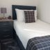 By The Bay in Peterhead: single bed with plaid throw and bedside lamp in a simple hotel room