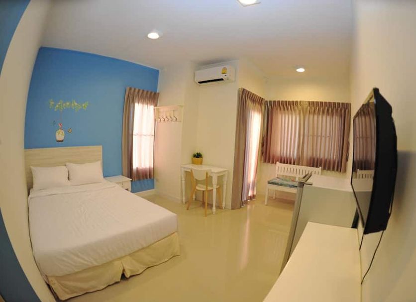 The Garden Living Bangkok room with bed, TV, desk, curtains, and windows