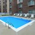 Outdoor pool at Fairfield Inn by Marriott Greensboro Airport in Greensboro beside a brick hotel building