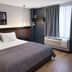Hotel Mirage Brooklyn guest room with queen bed, window, and city-view artwork in Brooklyn
