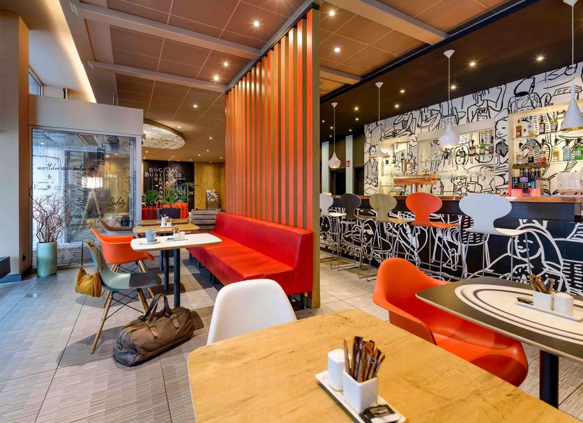 Ibis Hamburg Alsterring dining area in Hamburg with red seating and colorful bar counter