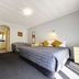 Kingswood Manor Motel in Whangarei: guest room with bed, armchair, desk, and bathroom doorway