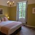 The Bedford Hotel Tavistock bedroom with king bed, chandelier, and window overlooking greenery