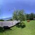 Hotel Garden in Torri Del Benaco with a lakeside lawn, trees, and a curved walkway under blue sky