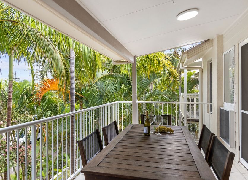 Sunset Cove Noosa balcony with dining table and tropical palm view in Noosaville