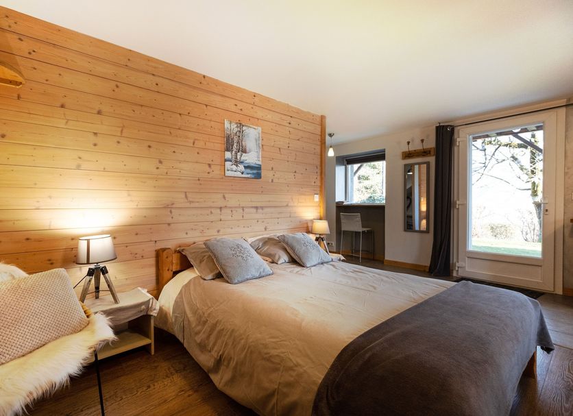 La Ferme De Noémie in Albertville guest room with wood-paneled wall, bed, and balcony door