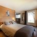 La Ferme De Noémie in Albertville guest room with wood-paneled wall, bed, and balcony door