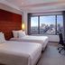 Grand Mercure Jakarta Harmoni room with twin beds, desk and city skyline view in Jakarta