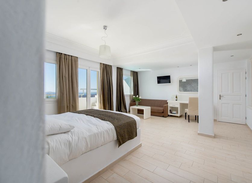 Tzekos Villas in Thera, bright guest room with bed, seating area and sea-view windows