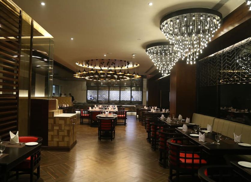 Ramada Encore by Wyndham Jalandhar restaurant interior with chandeliers and dining tables