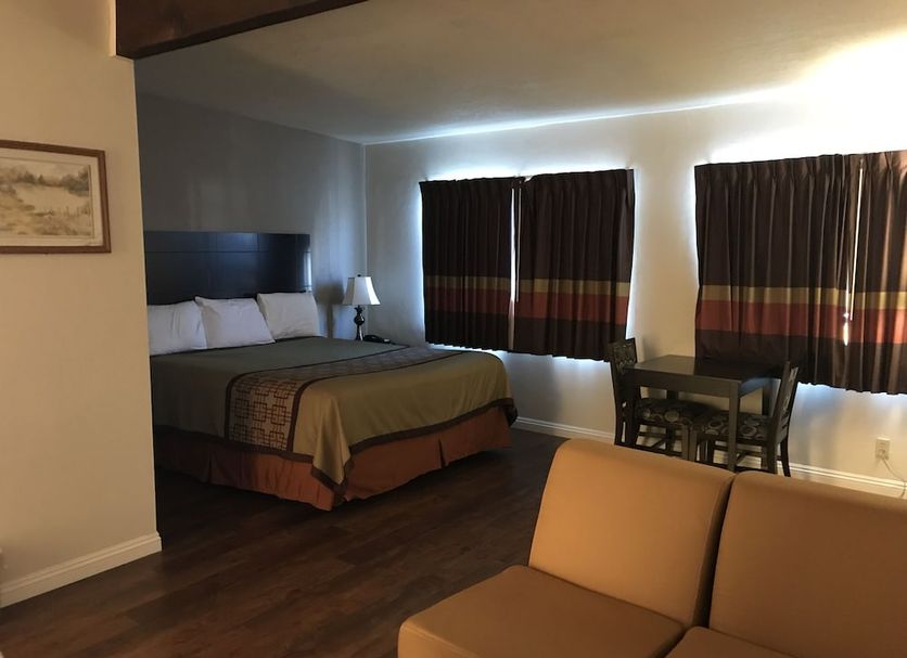 Manhattan Inn & Suites in Manhattan Beach guest room with king bed, table, and dark curtains