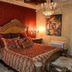 Olympia Villas in Stoupa: ornate bedroom with carved bed, chandelier and red patterned walls