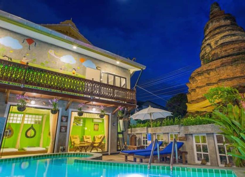 Chedi Home Chiang Mai courtyard pool with lounge chairs and a temple-style stupa at dusk