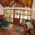 Hostal de la Laguna in Ushuaia, rustic lounge with wood-paneled ceiling, green chair, and front windows