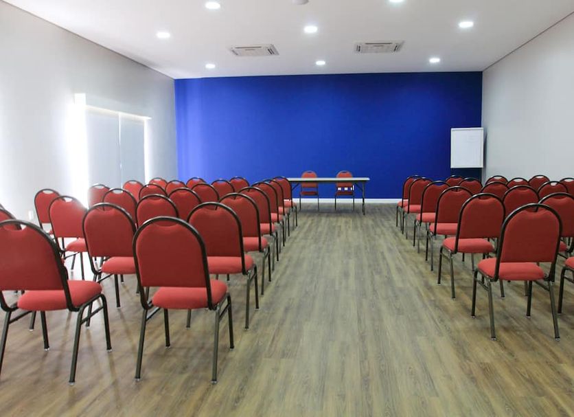The World Indaiatuba meeting room with rows of red chairs and a blue front wall