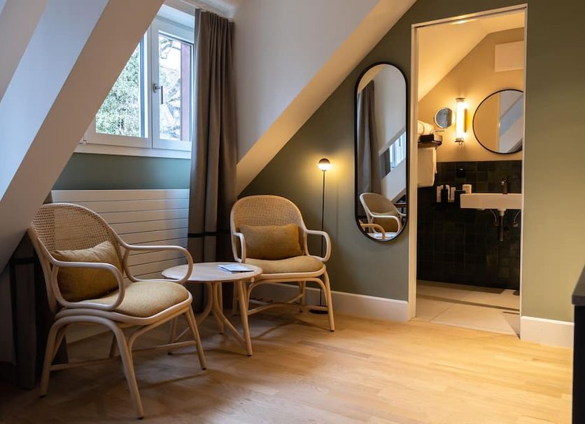 Boutique Hotel Waldhaus Birsfelden attic room with wicker chairs, small table and bathroom doorway