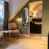 Boutique Hotel Waldhaus Birsfelden attic room with wicker chairs, small table and bathroom doorway