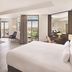 JA Beach Hotel, Dubai suite with king bed, seating area, and balcony views over greenery