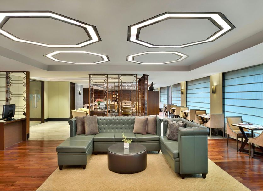 JW Marriott Hotel New Delhi Aerocity lounge with sectional seating, wood floors, and geometric ceiling lights