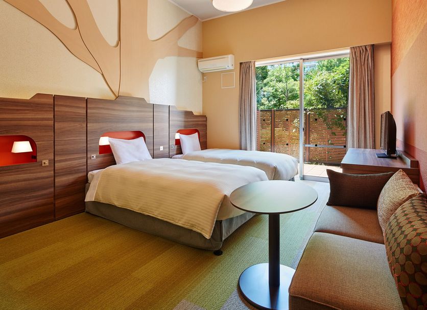 Mitsui Garden Hotel Prana Tokyo Bay room in Urayasu with two beds, sofa, and balcony view of greenery