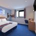 Travelodge London Twickenham guest room with double bed, desk, window and blue carpet