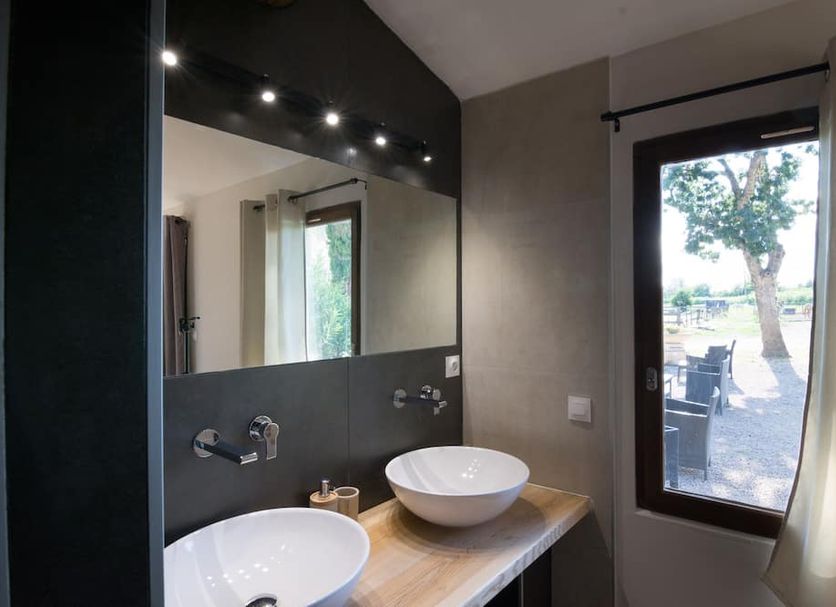 Le Mas d'Eymard in Arles, bathroom with double vessel sinks and a window overlooking outdoor seating