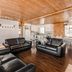 Auberge du Lac-a-l'Eau-Claire living room with leather sofas, wood ceiling and dining area in Saint-Alexis-des-Monts