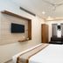 Grande Inn Tiruchirappalli guest room with king bed, sofa, TV, ceiling fan and window curtains