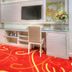 One One Bangkok Hotel room with wall-mounted TV, desk, chair, colorful carpet and floral arrangement