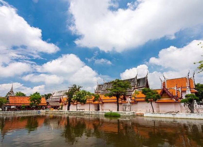 Sun Hotel in Phetchaburi by a canal with temple-style rooftops and cloudy sky reflection