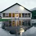Hotel Katla by Keahotels in Vik, white lodge exterior reflected on a wet paved courtyard at dusk