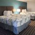 Motel 6 Crowley, La room with two double beds, lamp, desk, and bathroom vanity