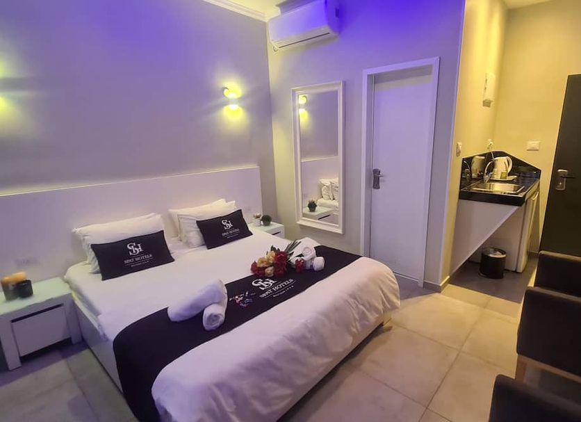 Spat Hotel Ashdod in Ashdod guest room with queen bed, wall mirror, and small desk nook