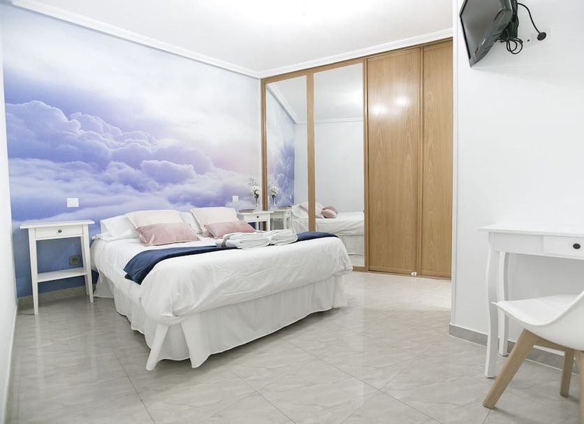 CH La Bañezana Madrid guest room with double bed, cloud mural wall, desk and wardrobe