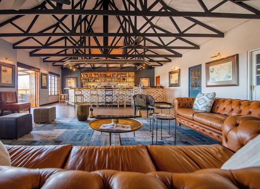 Gondwana Etosha Safari Lodge lounge in Okaukuejo with leather sofas, bar, and exposed beam ceiling