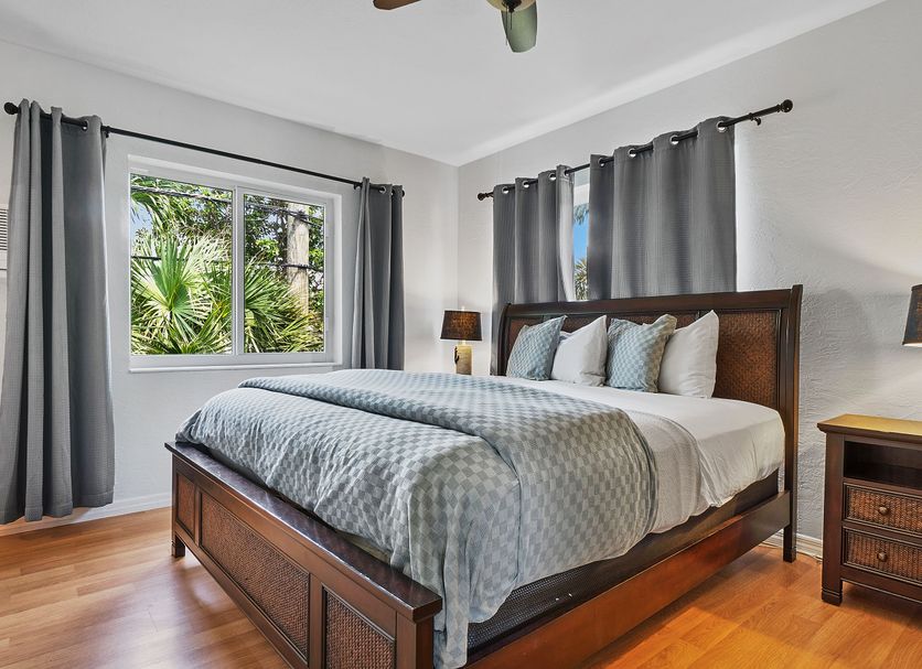 4145 By The Sea Inn & Suites in Lauderdale-by-the-Sea bedroom with wood bed, gray curtains and palm view