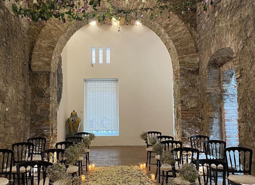 Hotel Boutique Casareyna in Puebla City: stone arch venue with rows of black chairs and floral aisle