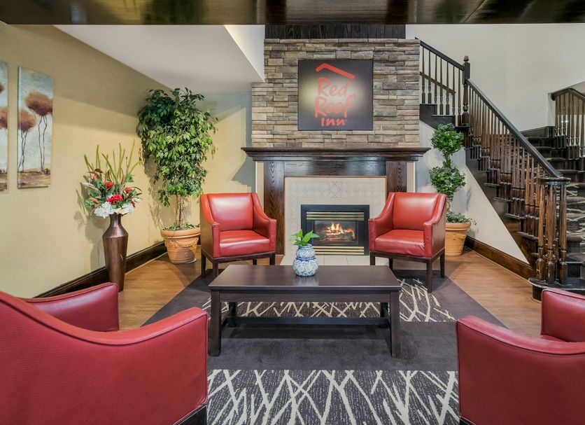 Red Roof Inn & Suites Knoxville East lobby lounge with red chairs and stone fireplace in Knoxville