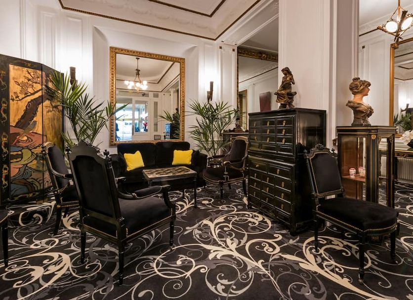 Hotel Peyris Opera in Paris lobby with ornate black chairs, patterned carpet and gold-framed mirror