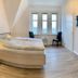 Gästehaus Seewarte Flensburg room with curved bed, lighthouse wall art, and chairs by windows