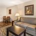 Best Western Plus Valdosta Hotel & Suites living room with sofa, coffee table, lamps and dining nook