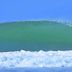 Hotel La Isla in Parrita: surfer riding a large green wave by the beach