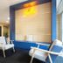 City Résidence Paris Saint-Maurice lobby seating area with blue lounge chairs and neon sign in Saint-Maurice