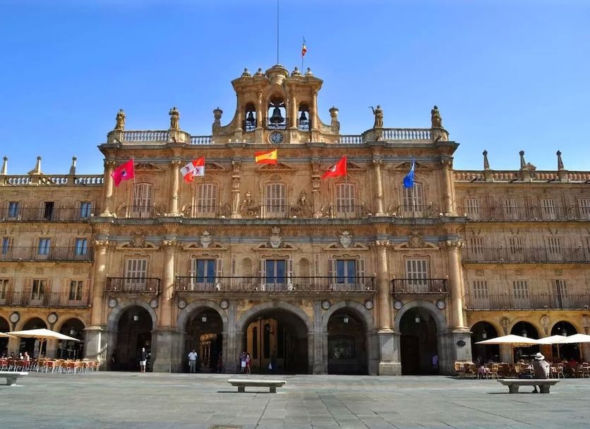 Hostal Santel San Marcos in Salamanca, historic stone building with arched entrance and flags