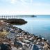 Barrier Island Station in Duck overlooks calm water, rocky shoreline, and a long pier