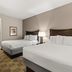 Americas Best Value Inn Byhalia guest room with two beds, lamp, and vanity mirror