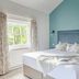 Bartley Lodge Hotel Southampton guest room with teal accent wall, king bed, window, and bedside tables