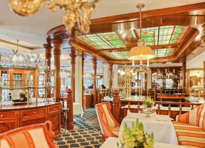 Seetelhotel Ahlbecker Hof in Heringsdorf, ornate restaurant with stained-glass ceiling and striped seating